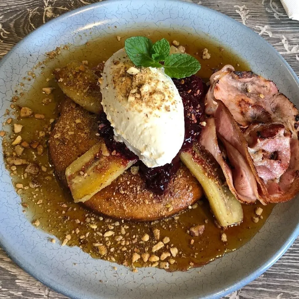 Close up of pancakes with banana, bacon, berry coulis & cream