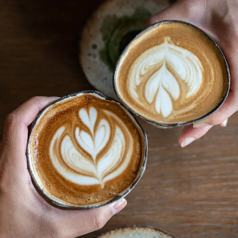 Overhead shot of two people holding their coffees together