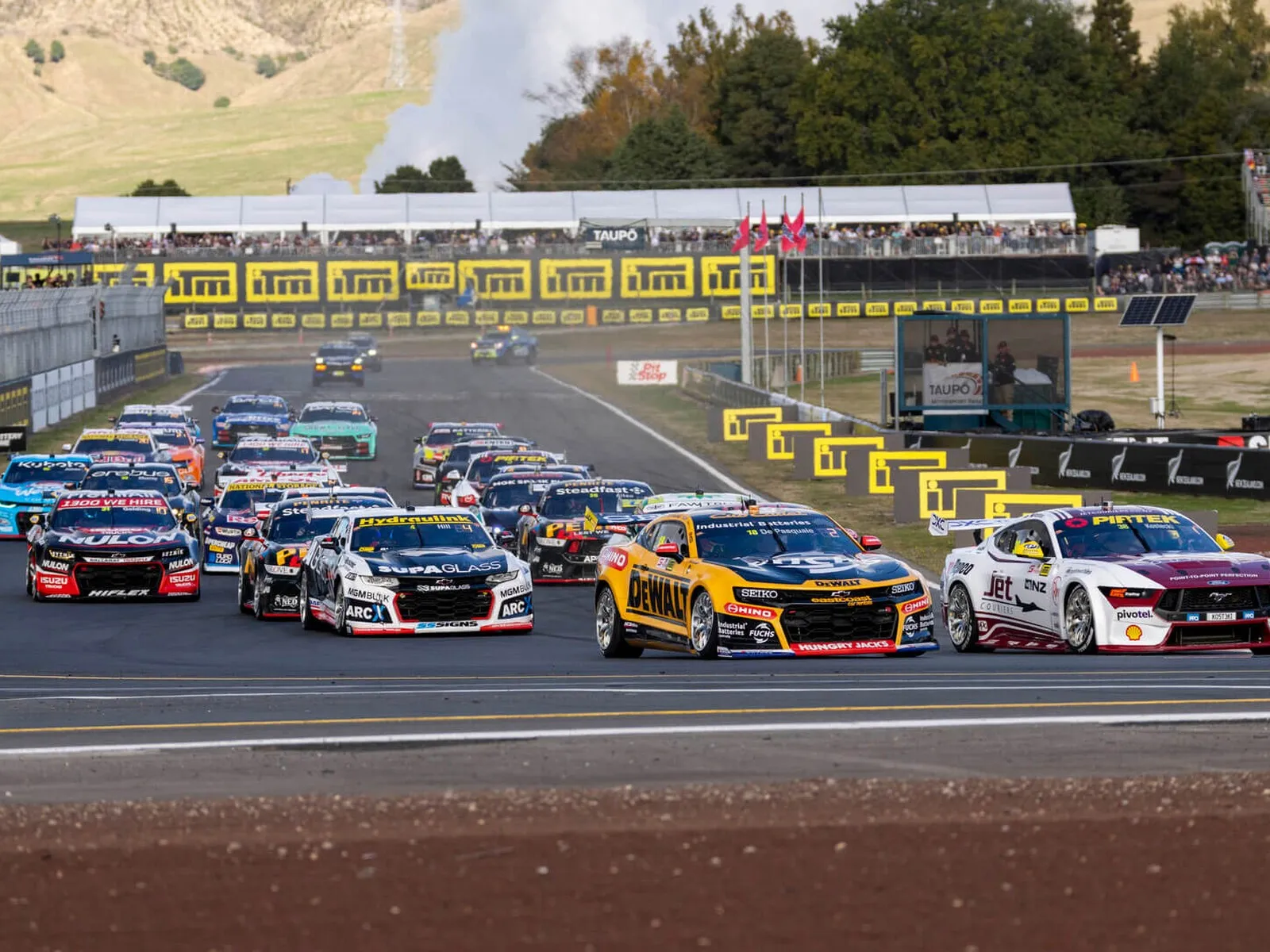 Supercars racing on racetrack with the crowd in the background