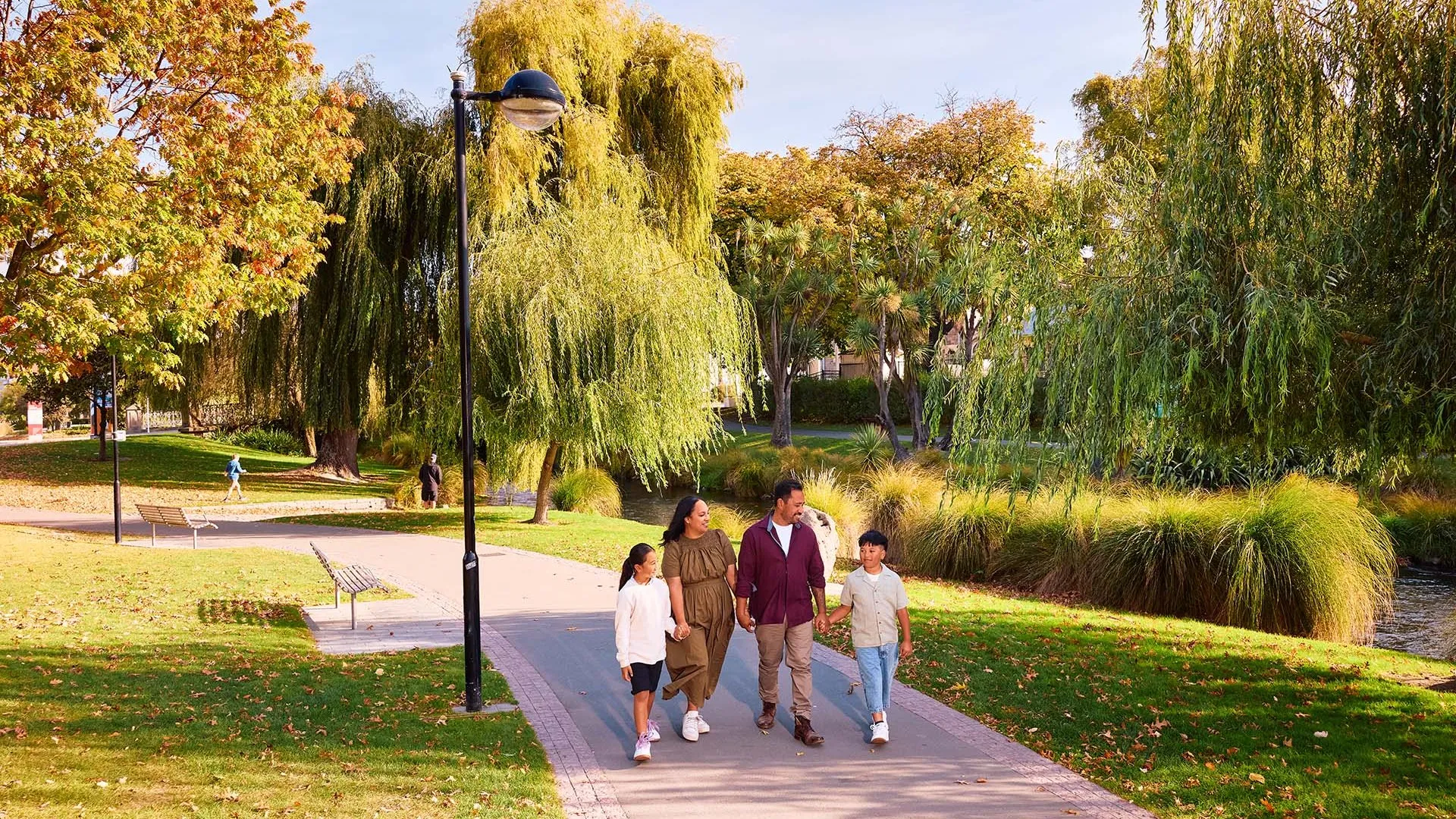 Family walking along the Avon Ōtākaro River in autumn