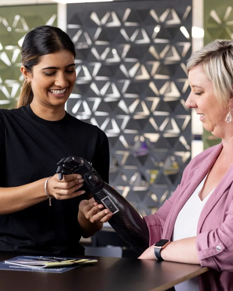 Lady fitting prosthetic hand on client.