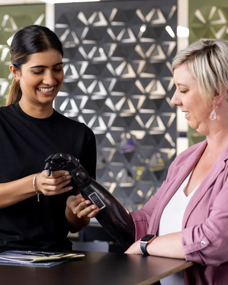 Lady fitting prosthetic hand on client.