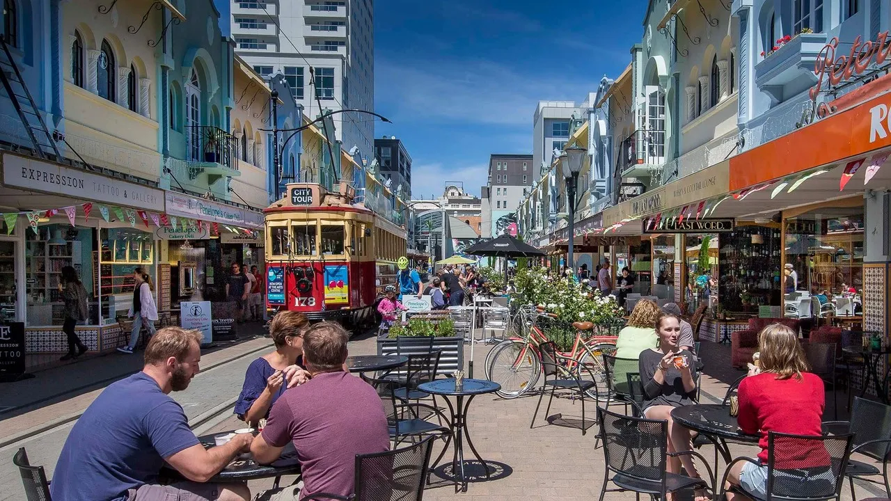 Tram moving down New Regent Street with lots of people sitting outside cafes enjoying coffee.