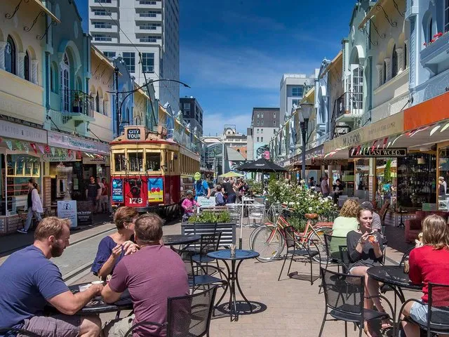 Tram moving down New Regent Street with lots of people sitting outside cafes enjoying coffee.