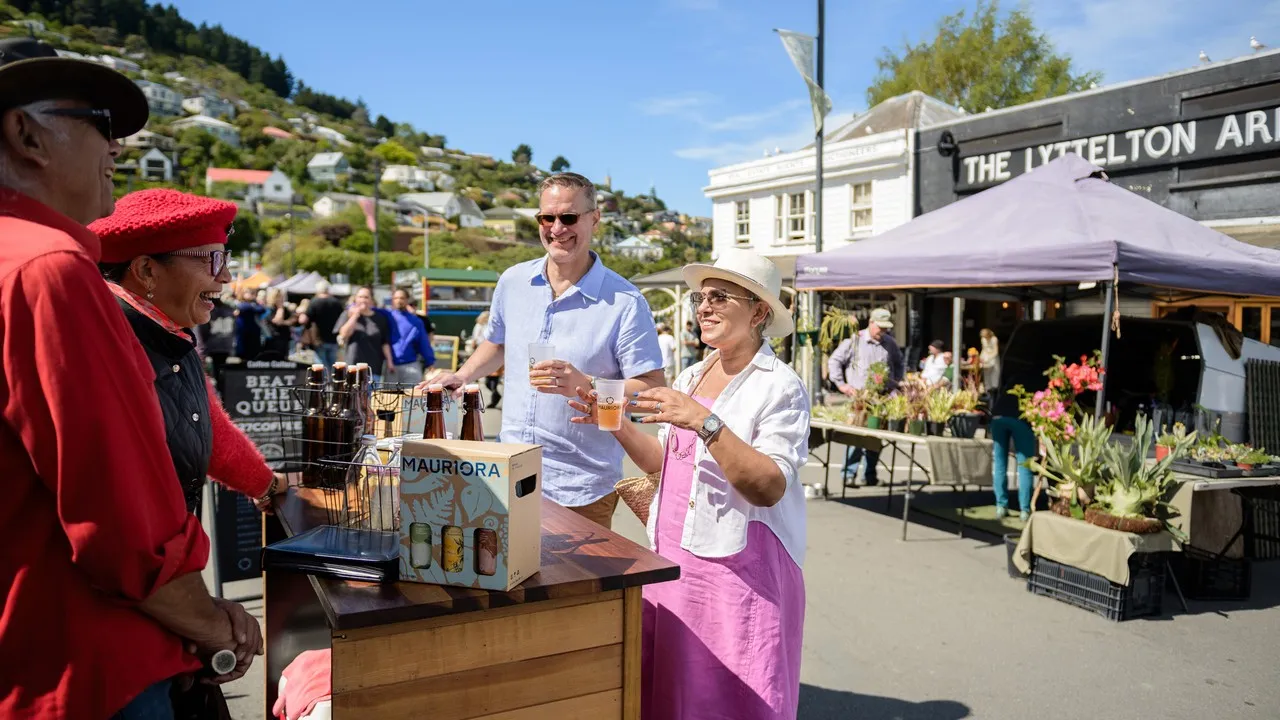A couple enjoyng beverage tastings at the Lyttelton Farmers Market.