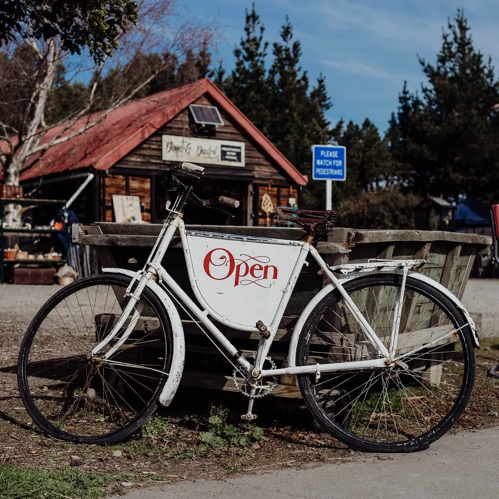 Bike with 'Open' sign outside Done and Dusted vintage store in Cust