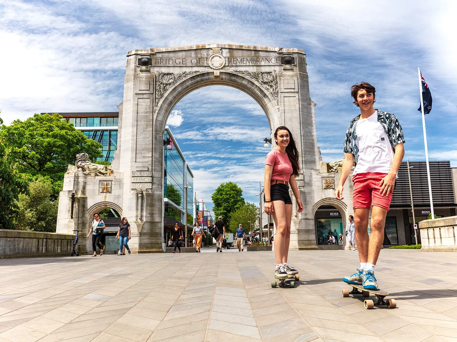 Two students skateboarding in front of the Bridge Of Remembrance.