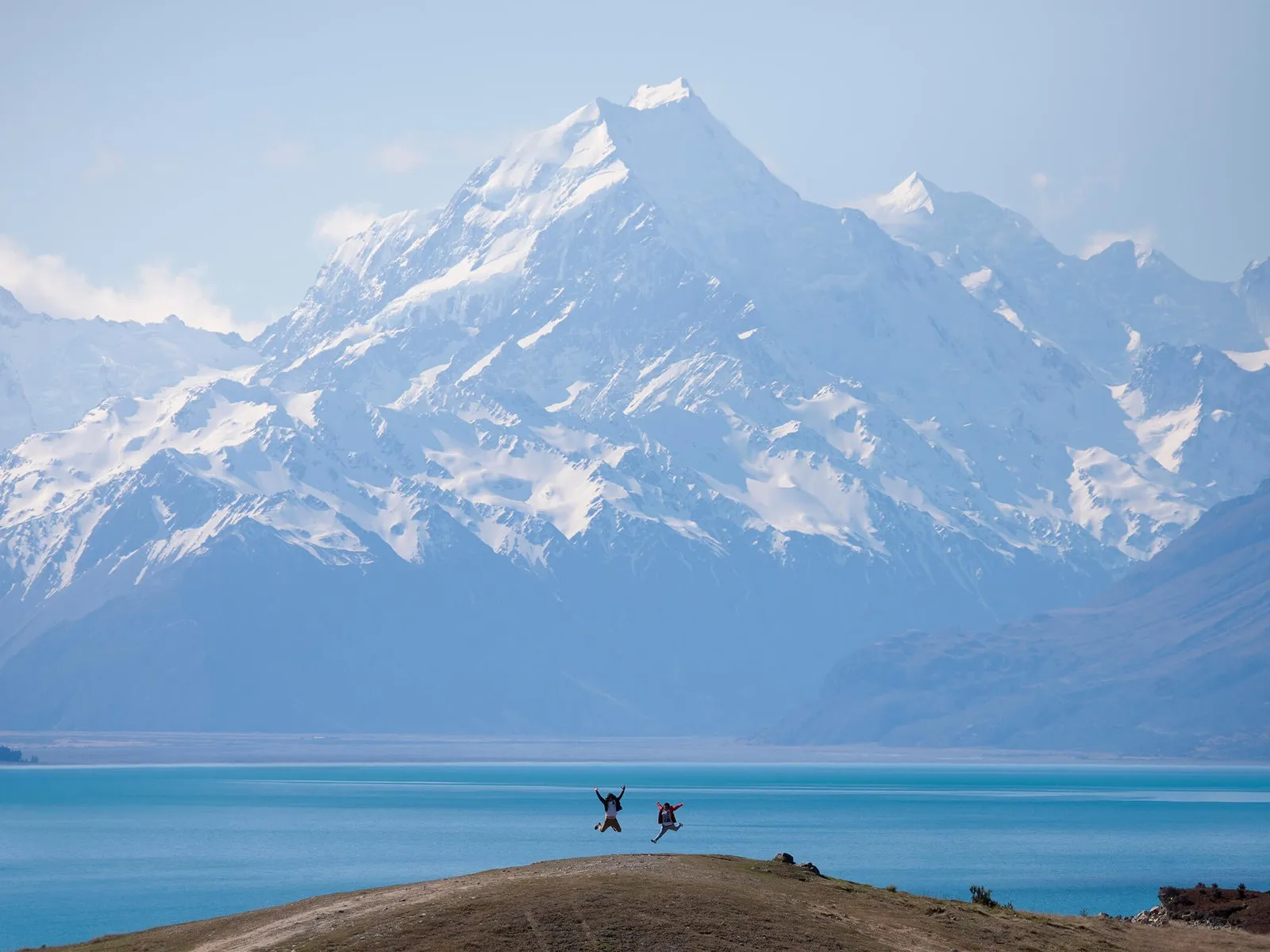 Two people jumping in front of Mt Cook/Aoraki Lake Pukaki