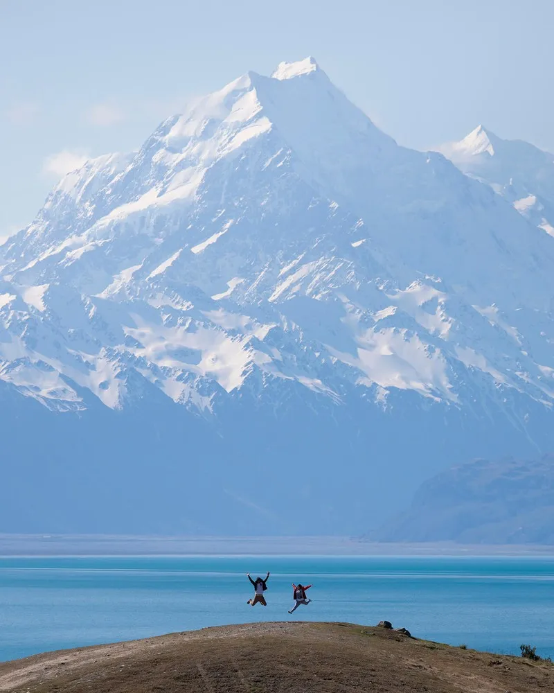 Two people jumping in front of Mt Cook/Aoraki Lake Pukaki