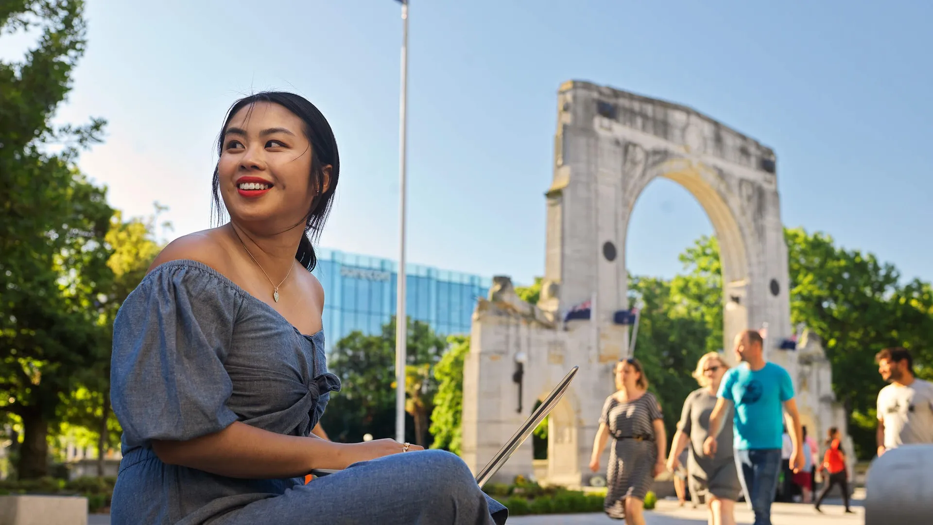 Girl working on her laptop in front of the Bridge of Remembrance.
