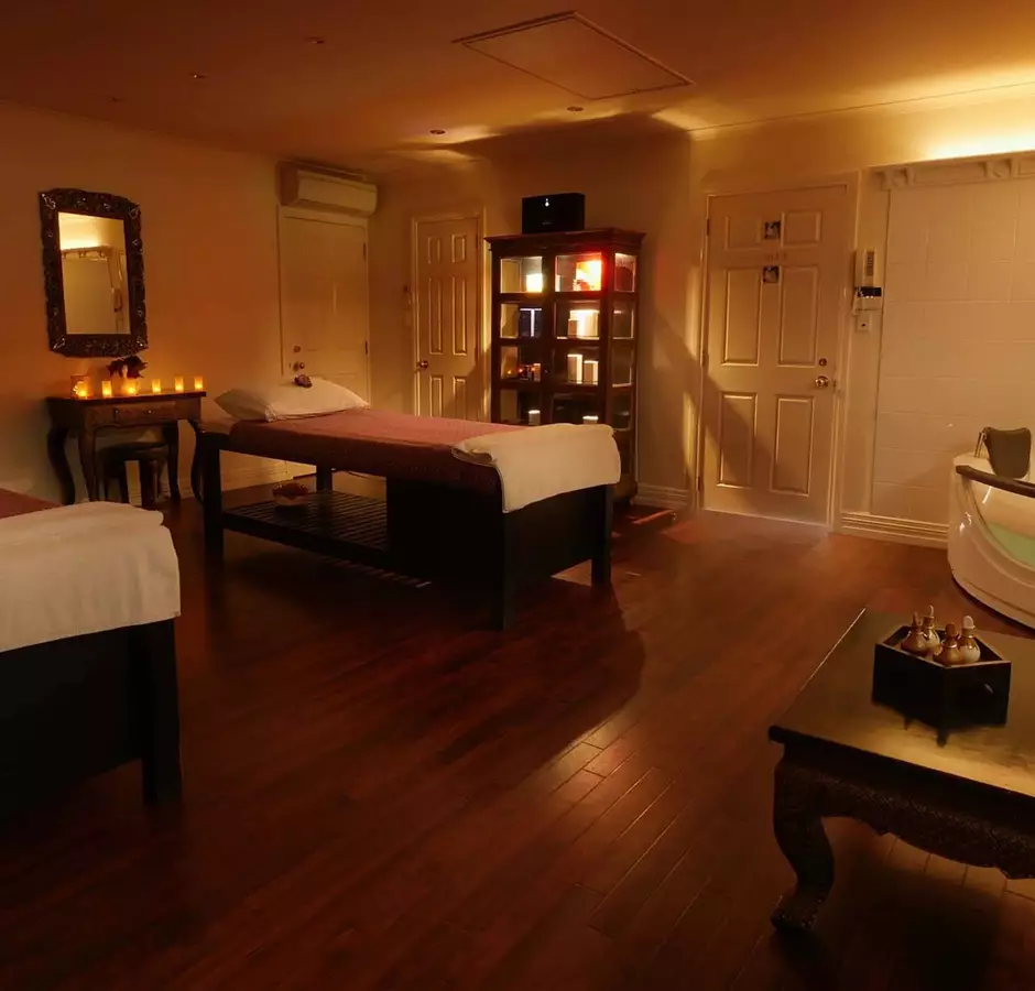 Room at Lotus Day Spa, dimly lit with candles, spa beds and spa bath.