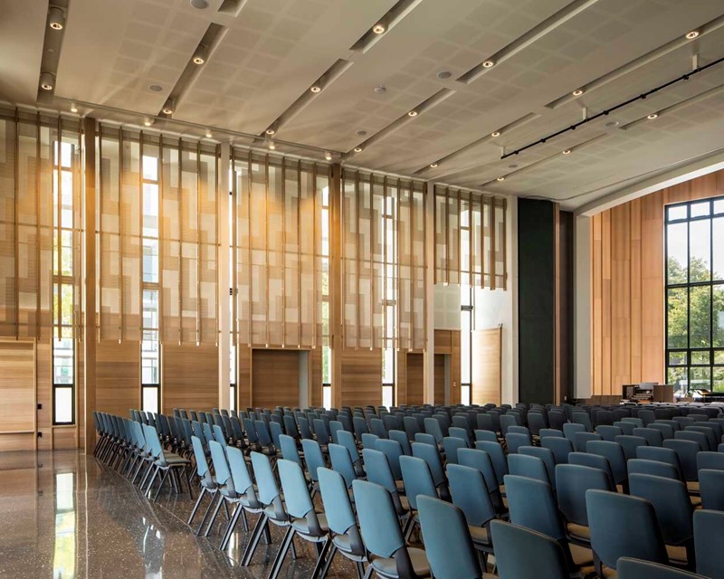 Image shows a function space set up in theatre style, the venue has high ceilings and wooden panels line the walls