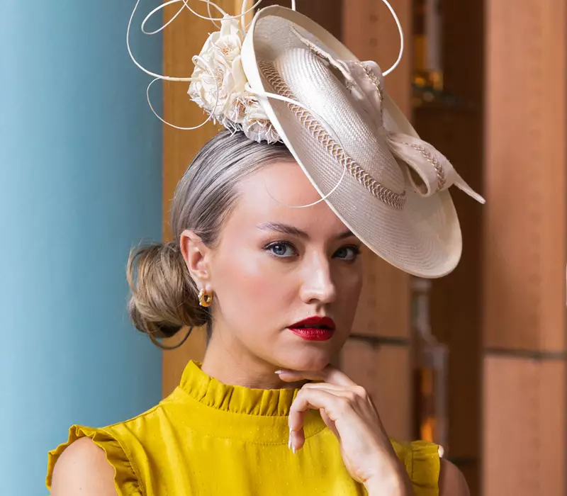 Model dressed in yellow with a nude hat for the races
