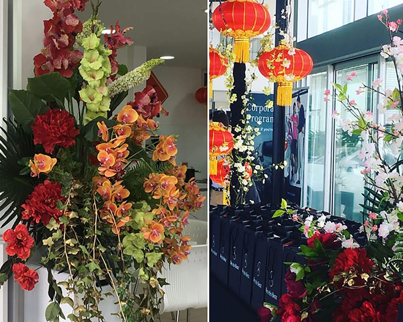 Split image, on the right a tall bouquet of red, green and orange flowers. On the right, Chinese hanging lanterns with orchids draped through