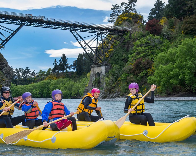 Participants paddle Canoes with the bungee bridge in the background 