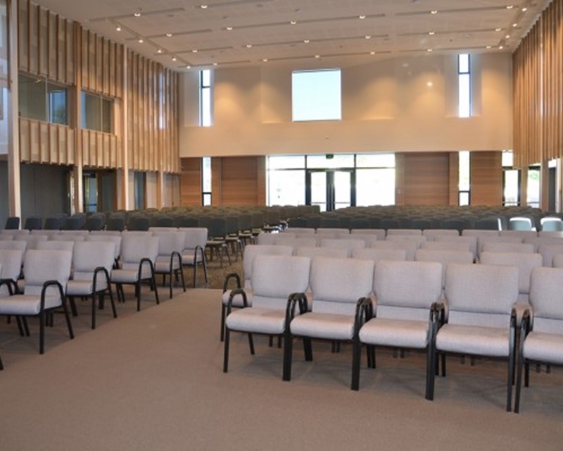 Image shows a function space set up in theatre style, the venue has high ceilings and wooden panels line the walls