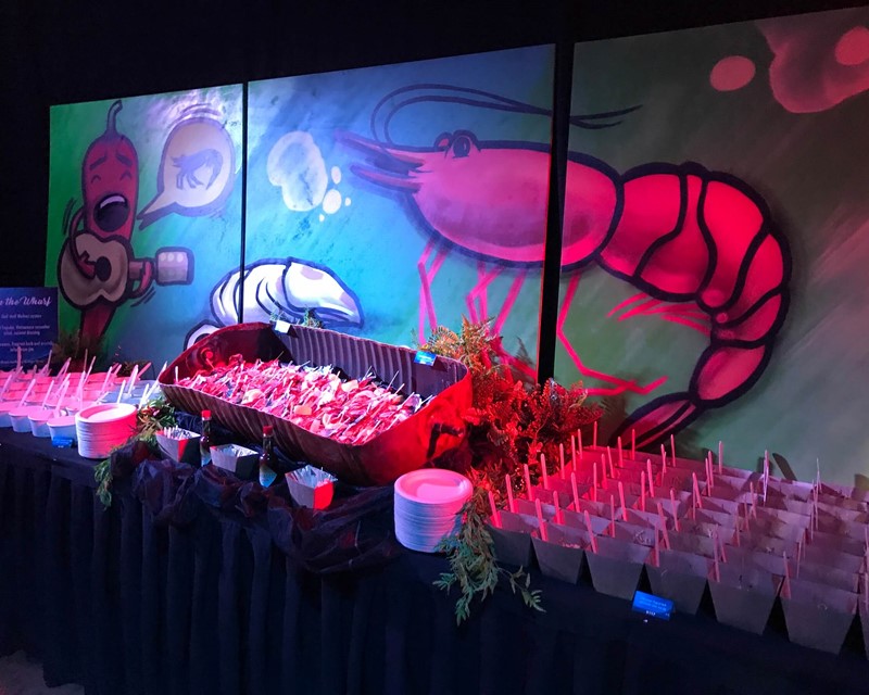 Collective Concepts Food Station, individually boxed portions with a painted mural of animated seafood behind the table. 