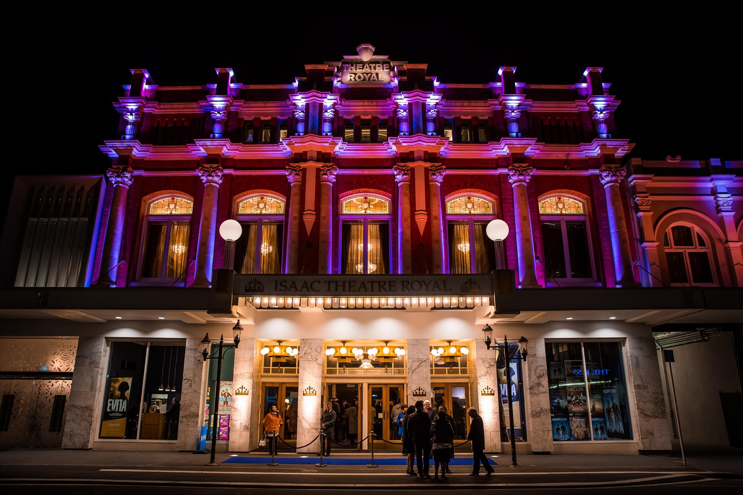 Isaac Theatre Royal night lights illuminating the building in purple and red 